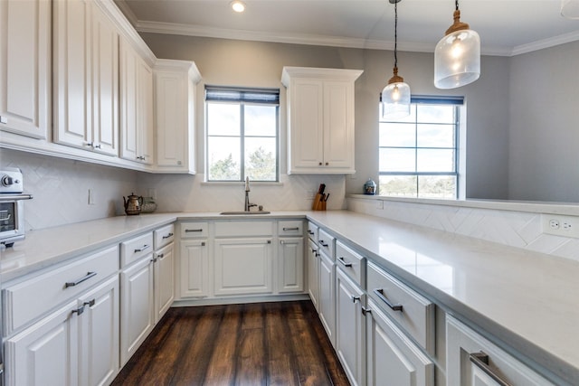 kitchen featuring a sink, white cabinets, backsplash, dark wood-style floors, and crown molding