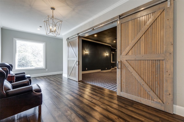 living area featuring baseboards, a barn door, ornamental molding, and wood finished floors