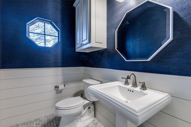 bathroom featuring toilet, a wainscoted wall, and a sink