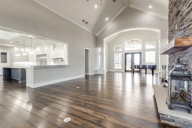 living area with visible vents, dark wood-style floors, crown molding, high vaulted ceiling, and a notable chandelier