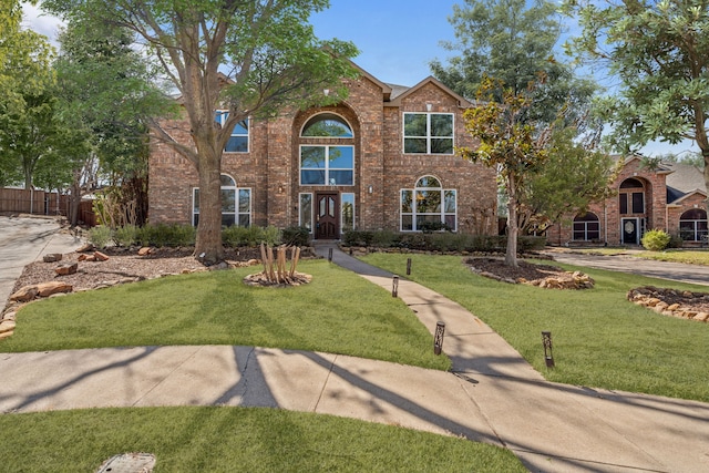 traditional home featuring a front yard and brick siding