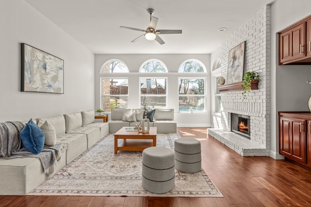 living room with a wealth of natural light, a brick fireplace, baseboards, and wood finished floors