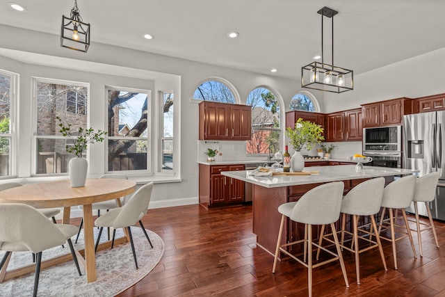 kitchen with dark wood-style floors, a center island, stainless steel appliances, hanging light fixtures, and backsplash