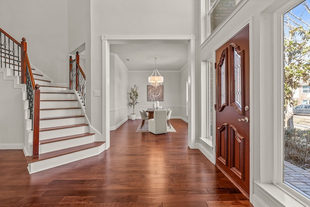 foyer entrance with plenty of natural light, stairs, baseboards, and dark wood-type flooring