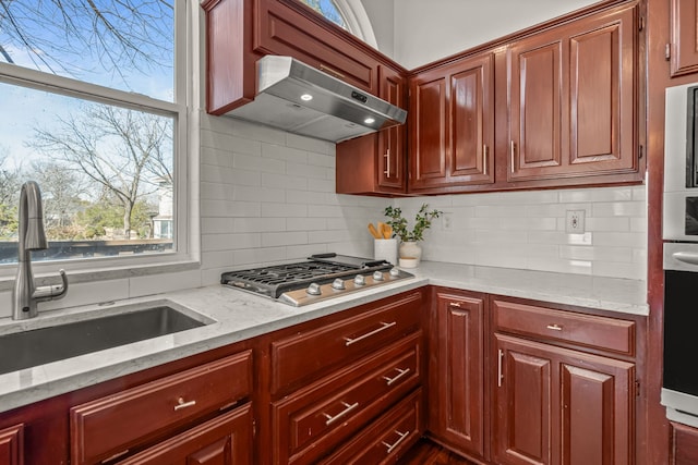 kitchen featuring backsplash, stainless steel gas cooktop, extractor fan, and a sink