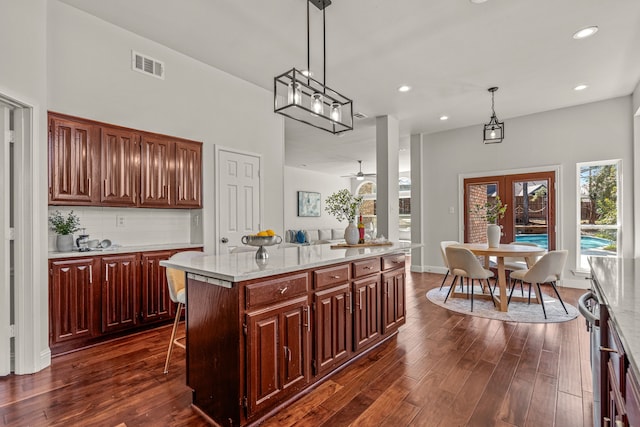 kitchen featuring hanging light fixtures, visible vents, backsplash, and dark wood-style flooring