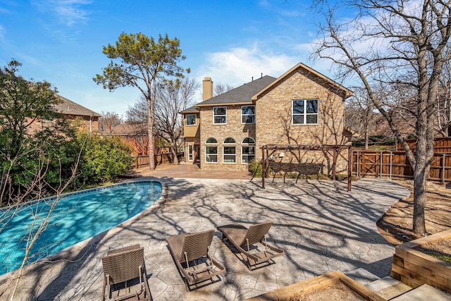 back of property with a patio, brick siding, a chimney, and a fenced backyard