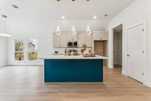 kitchen with visible vents, lofted ceiling, appliances with stainless steel finishes, light countertops, and light wood-type flooring