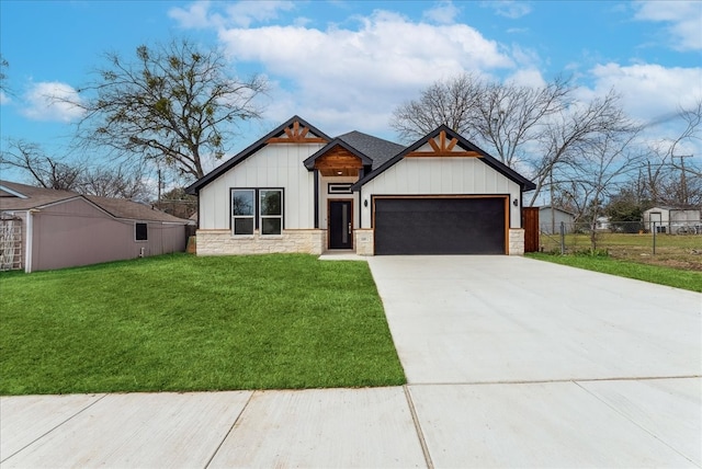 view of front of home with a garage, concrete driveway, stone siding, fence, and a front lawn