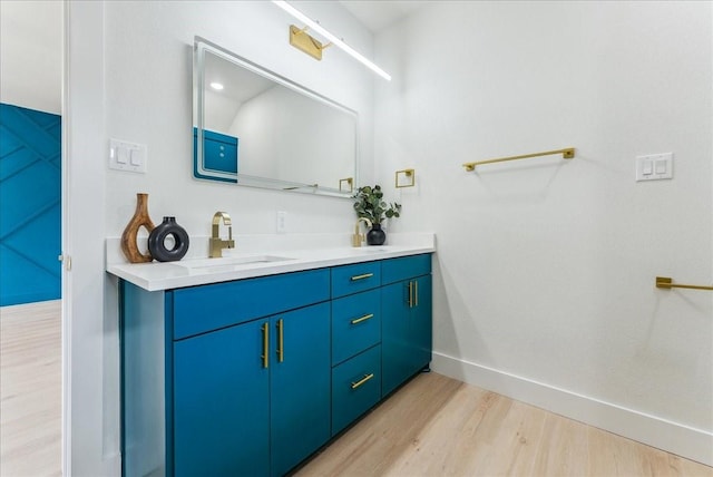 bathroom featuring double vanity, baseboards, a sink, and wood finished floors