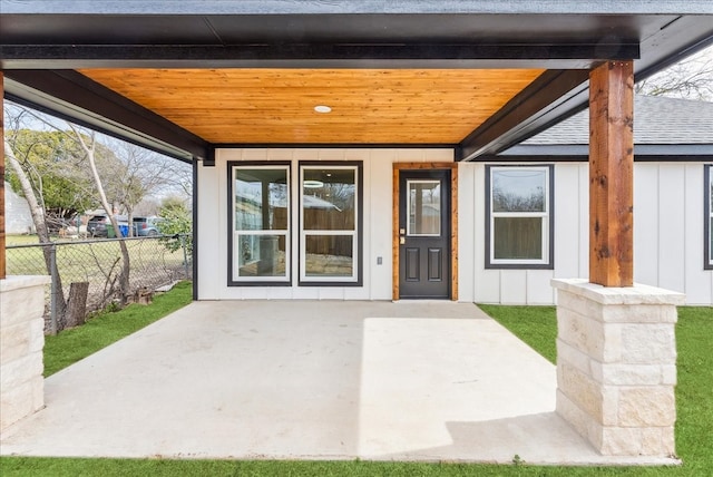 entrance to property featuring fence, board and batten siding, and a patio