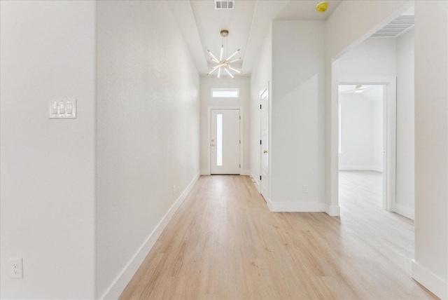 doorway with light wood-style floors, visible vents, baseboards, and an inviting chandelier