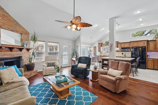 living room with a brick fireplace, hardwood / wood-style floors, recessed lighting, high vaulted ceiling, and a ceiling fan