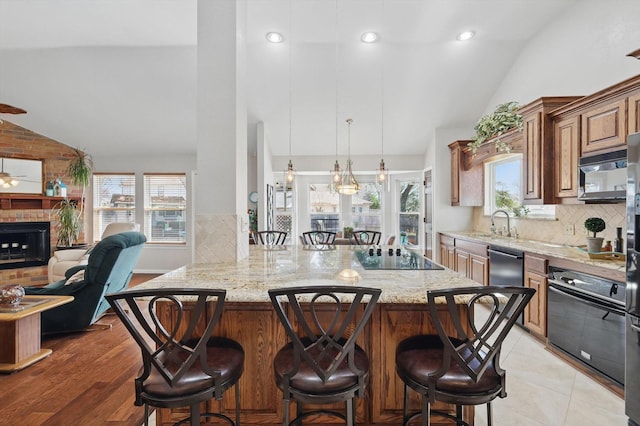 kitchen with light stone counters, lofted ceiling, black appliances, and a breakfast bar