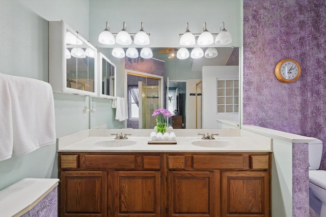 bathroom featuring a shower stall, toilet, double vanity, and a sink