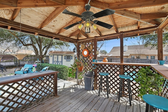 wooden deck featuring a storage shed, an outdoor structure, a ceiling fan, and fence