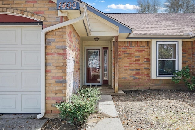 entrance to property featuring brick siding and roof with shingles