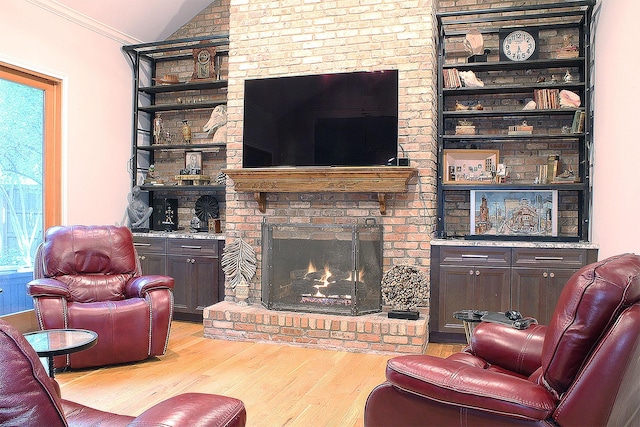 living room with vaulted ceiling, a brick fireplace, light wood-style flooring, and crown molding