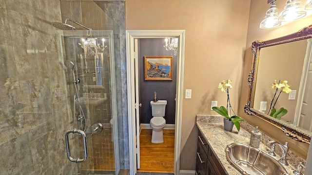 full bathroom with toilet, a stall shower, baseboards, and vanity