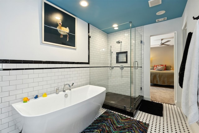 bathroom with a stall shower, a freestanding tub, visible vents, and tile walls