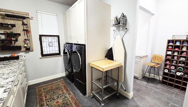 clothes washing area with washer and dryer, cabinet space, and baseboards