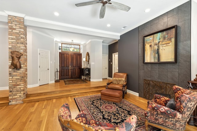 entryway with light wood-type flooring, a ceiling fan, baseboards, and crown molding