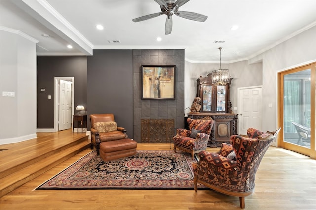 living area with wood finished floors, visible vents, and crown molding