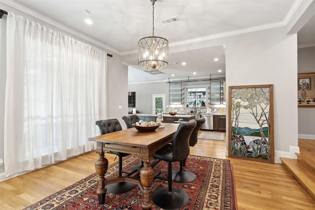 dining room featuring a chandelier, visible vents, baseboards, light wood-type flooring, and crown molding