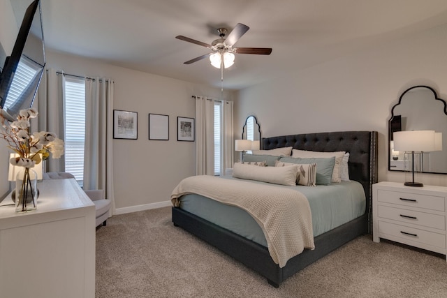 bedroom featuring light carpet, ceiling fan, multiple windows, and baseboards