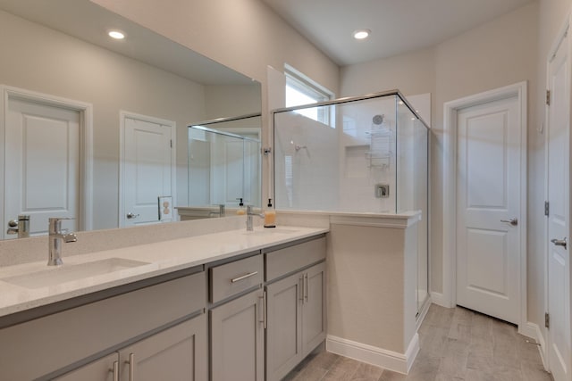 bathroom with double vanity, a stall shower, wood finished floors, a sink, and recessed lighting