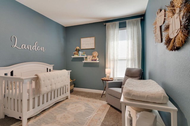 bedroom with a nursery area, light carpet, and baseboards