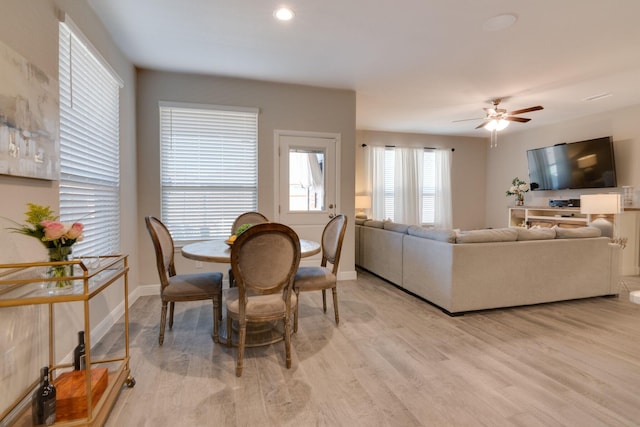 dining area featuring light wood-type flooring, baseboards, and a ceiling fan