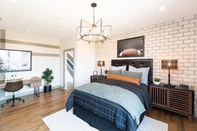 bedroom featuring a notable chandelier, recessed lighting, an accent wall, wood finished floors, and baseboards