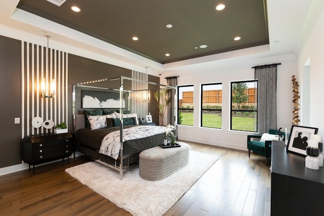 bedroom featuring a raised ceiling, crown molding, baseboards, and wood finished floors