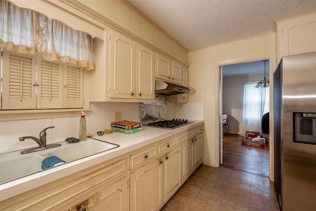 kitchen with under cabinet range hood, stainless steel appliances, a sink, light countertops, and tasteful backsplash