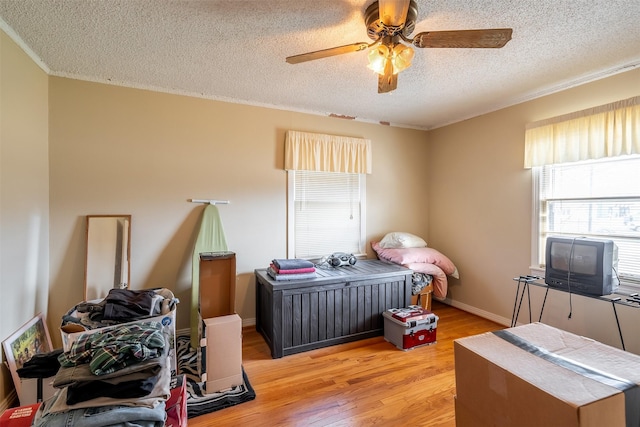 bedroom with light wood-style flooring, multiple windows, ceiling fan, and a textured ceiling