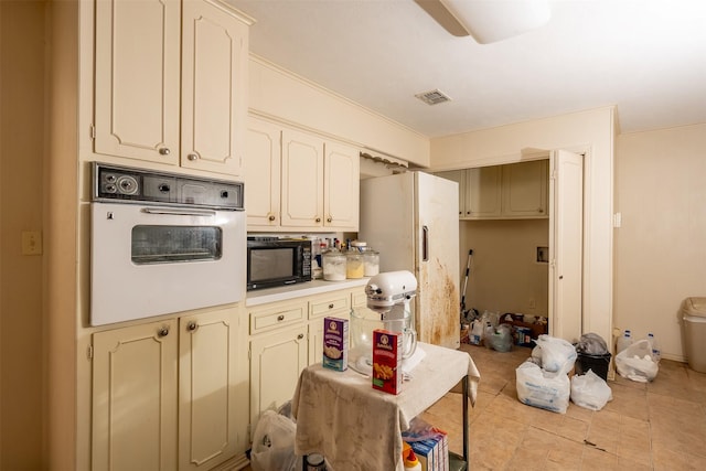 kitchen featuring light tile patterned floors, light countertops, visible vents, cream cabinets, and white appliances