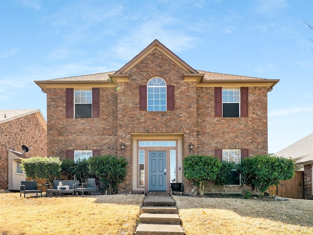 view of front of property with brick siding, a front yard, and fence