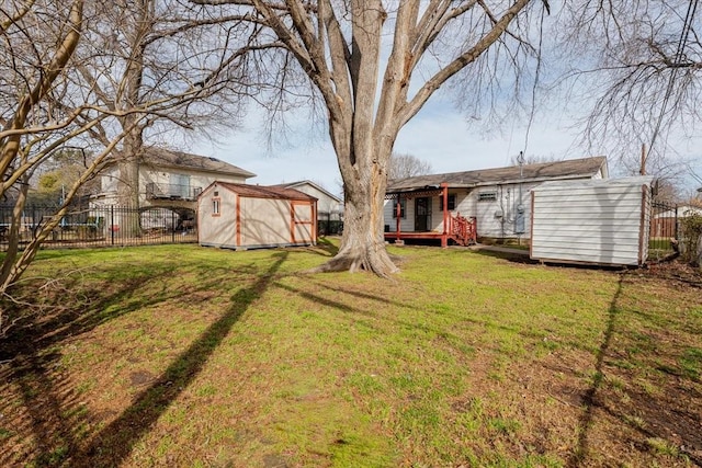 view of yard with an outbuilding, fence, a deck, and a storage unit