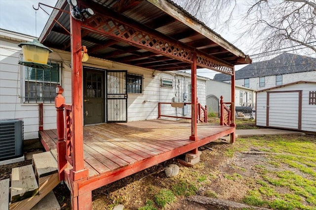 wooden terrace with central AC unit, a storage unit, and an outdoor structure