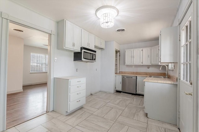 kitchen with visible vents, stainless steel appliances, a sink, and light countertops