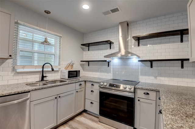 kitchen with visible vents, wall chimney exhaust hood, stainless steel appliances, open shelves, and a sink