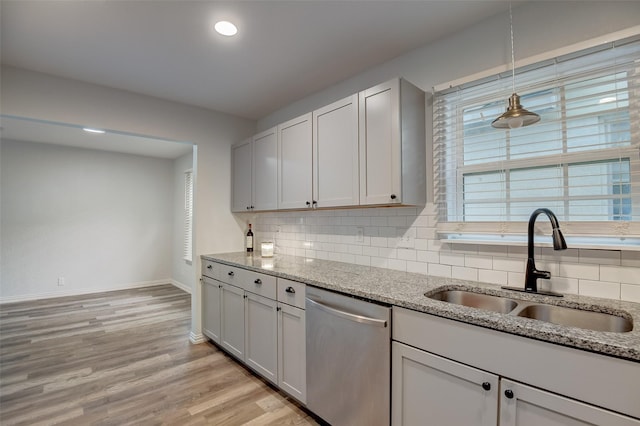 kitchen with a sink, light stone countertops, tasteful backsplash, and stainless steel dishwasher