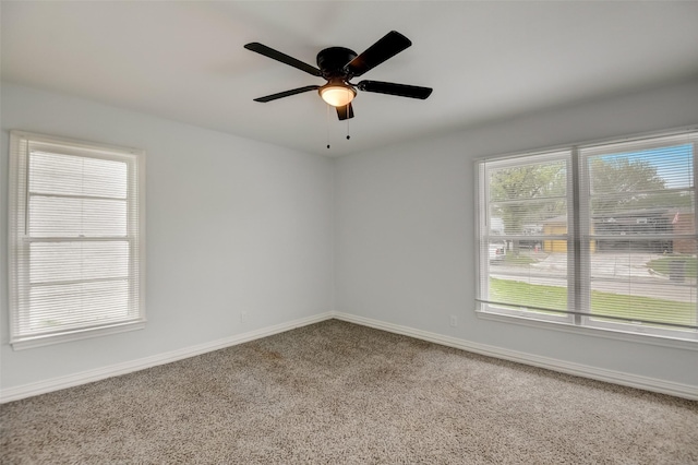 carpeted empty room featuring ceiling fan and baseboards