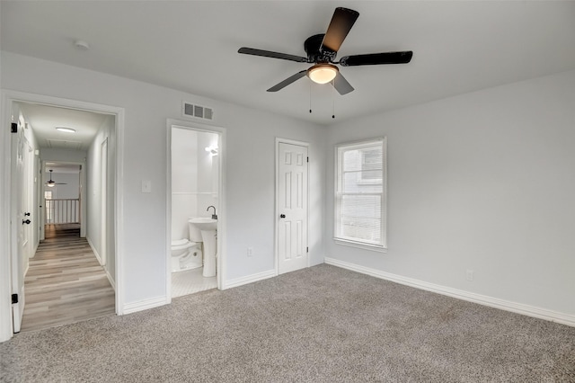 unfurnished bedroom featuring light colored carpet, visible vents, baseboards, ensuite bath, and attic access