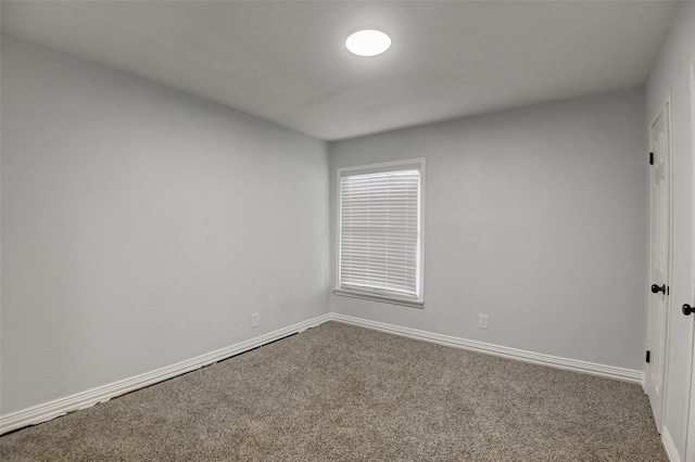 empty room with baseboards and dark colored carpet