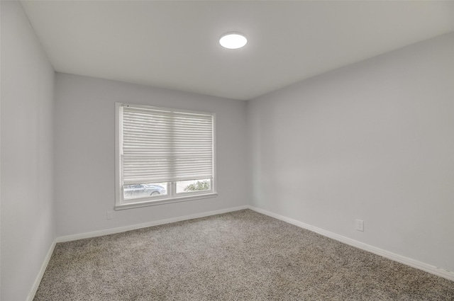 carpeted empty room featuring baseboards