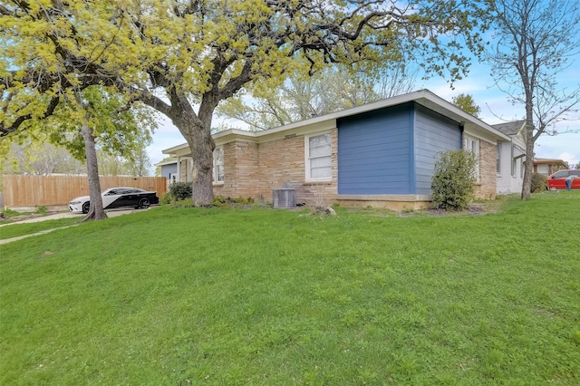 view of front facade featuring cooling unit, fence, and a front lawn