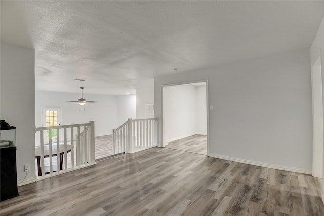 spare room featuring a textured ceiling, wood finished floors, and baseboards