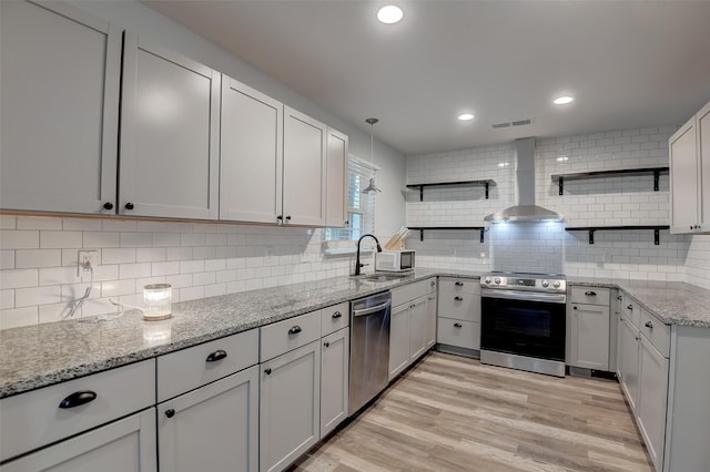 kitchen with visible vents, wall chimney exhaust hood, stainless steel appliances, open shelves, and a sink